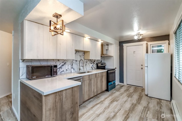 kitchen with pendant lighting, sink, decorative backsplash, a baseboard heating unit, and stainless steel appliances