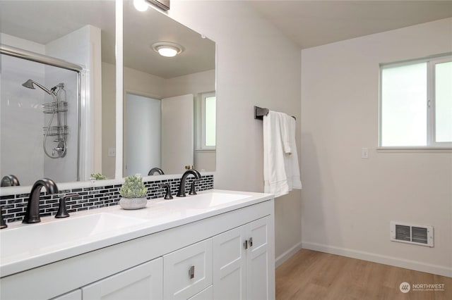 bathroom with vanity, a shower with shower door, hardwood / wood-style floors, and decorative backsplash