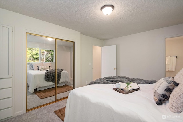 carpeted bedroom featuring a textured ceiling and a closet