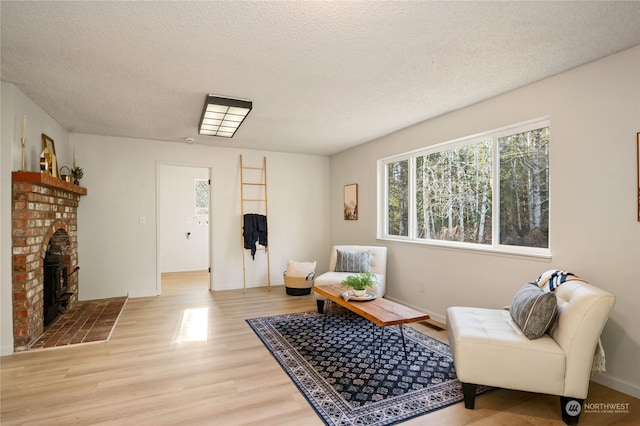 living room with a fireplace, light hardwood / wood-style floors, and a textured ceiling