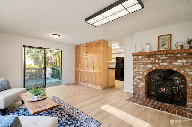 living room featuring a wood stove, a textured ceiling, and light hardwood / wood-style flooring