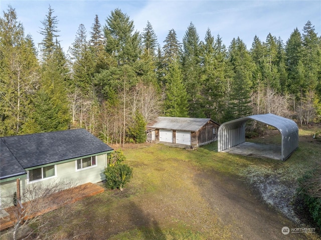 view of yard featuring a carport, a garage, and an outbuilding