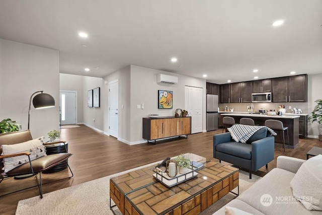 living room with baseboards, dark wood-style flooring, a wall mounted air conditioner, and recessed lighting