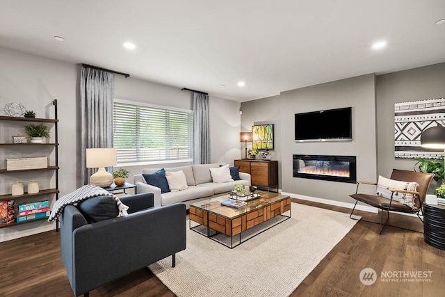 living area featuring dark wood-type flooring, a glass covered fireplace, baseboards, and recessed lighting