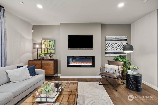 living room featuring recessed lighting, baseboards, wood finished floors, and a glass covered fireplace