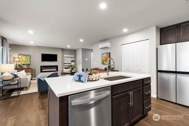 kitchen with a center island with sink, appliances with stainless steel finishes, open floor plan, light countertops, and a sink