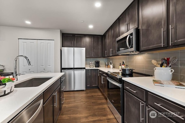 kitchen with a sink, stainless steel appliances, light countertops, and dark brown cabinetry