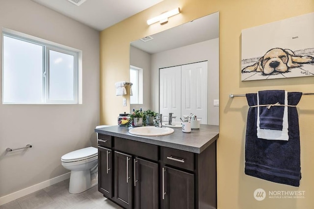 bathroom featuring toilet, baseboards, a closet, and vanity