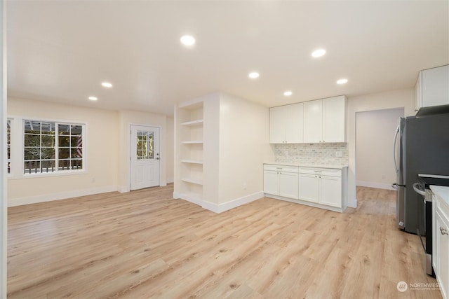 kitchen featuring built in features, appliances with stainless steel finishes, white cabinetry, light hardwood / wood-style floors, and decorative backsplash