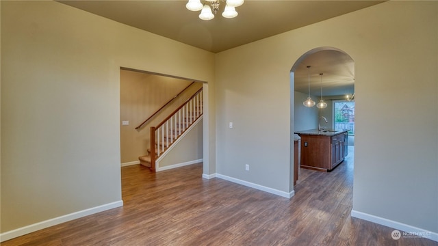 empty room with dark hardwood / wood-style flooring, a chandelier, and sink