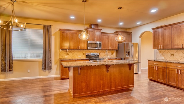 kitchen featuring appliances with stainless steel finishes, a breakfast bar area, a kitchen island with sink, and hanging light fixtures