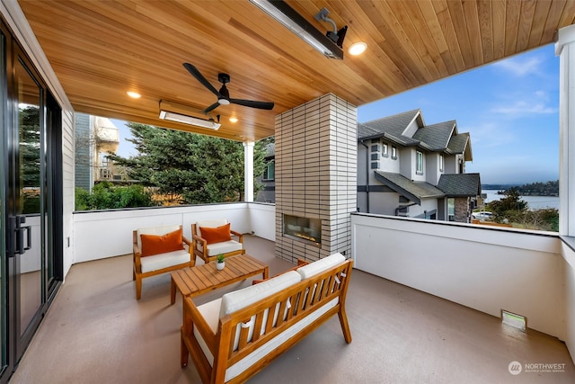 view of patio featuring a water view, ceiling fan, and an outdoor living space with a fireplace