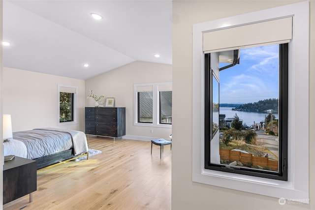 bedroom featuring a water view, lofted ceiling, and light hardwood / wood-style flooring