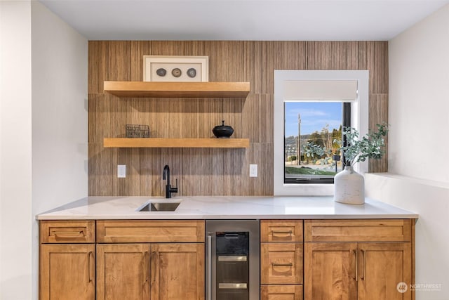 bar featuring light stone counters, sink, and beverage cooler