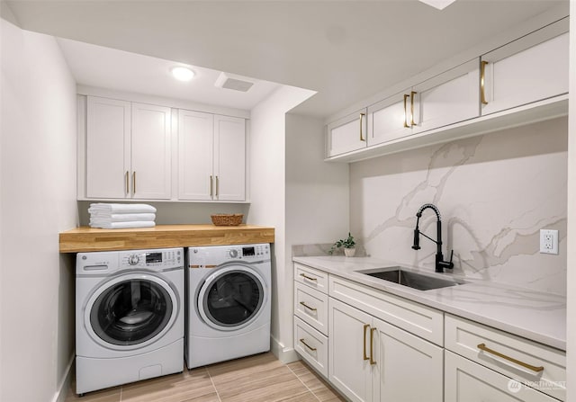 washroom with sink, washing machine and dryer, and cabinets