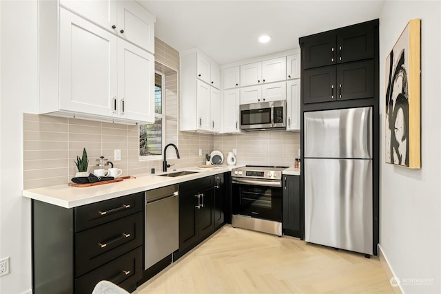 kitchen featuring sink, light parquet floors, stainless steel appliances, white cabinets, and decorative backsplash