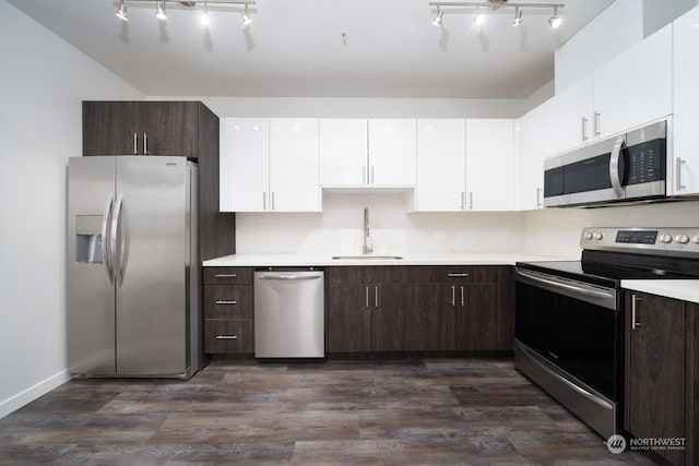 kitchen with appliances with stainless steel finishes, sink, white cabinets, dark brown cabinetry, and dark wood-type flooring