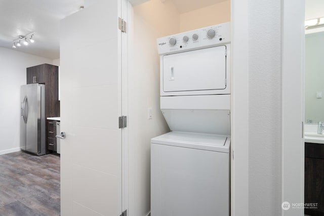 laundry area featuring stacked washer / drying machine and light hardwood / wood-style flooring