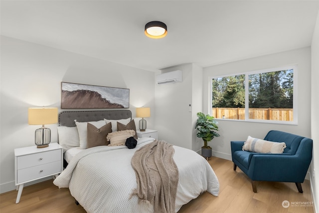 bedroom featuring a wall unit AC and light hardwood / wood-style flooring