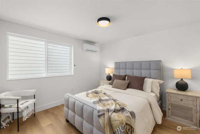 bedroom with a wall mounted AC and light wood-type flooring