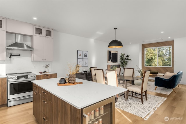 kitchen with pendant lighting, wall chimney range hood, white cabinetry, stainless steel electric range oven, and beverage cooler