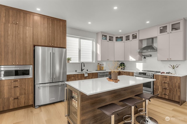 kitchen featuring appliances with stainless steel finishes, sink, wall chimney range hood, and white cabinets