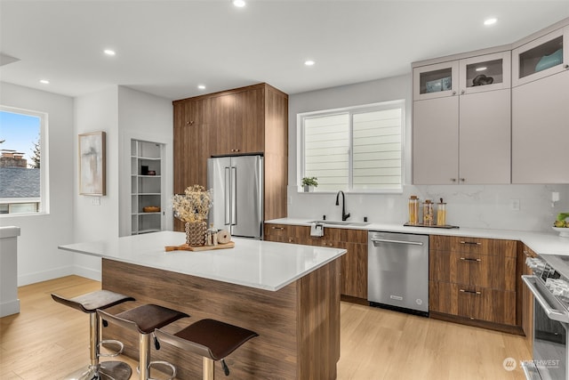 kitchen with sink, a breakfast bar area, light hardwood / wood-style flooring, appliances with stainless steel finishes, and a kitchen island