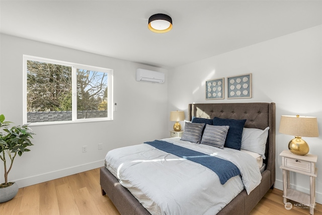 bedroom with a wall unit AC and light hardwood / wood-style floors