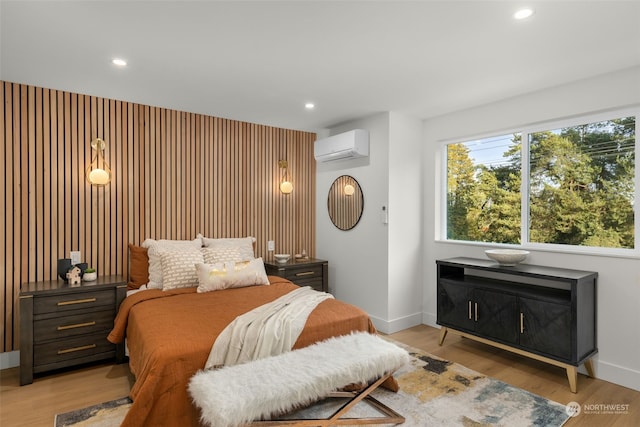 bedroom featuring light hardwood / wood-style floors and a wall mounted AC