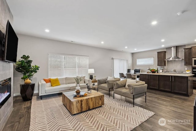 living room with a tiled fireplace and light hardwood / wood-style flooring