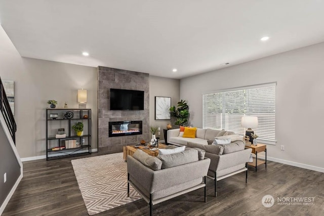 living room featuring a tiled fireplace and dark wood-type flooring