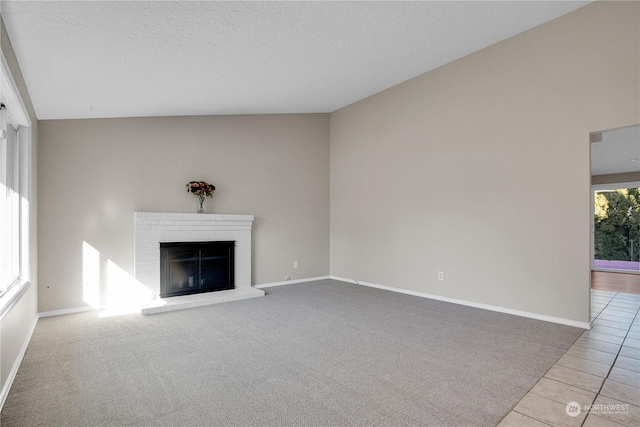 unfurnished living room with a brick fireplace, light colored carpet, and a textured ceiling