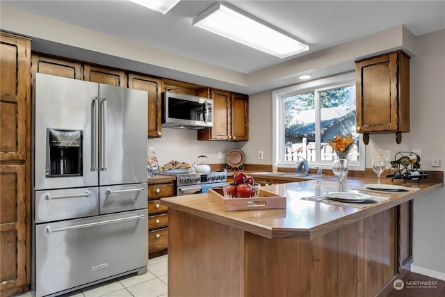 kitchen featuring light tile patterned floors, stainless steel appliances, and kitchen peninsula