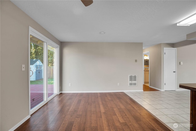 unfurnished room with heating unit, a textured ceiling, and light wood-type flooring