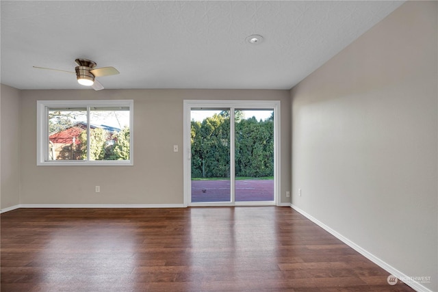 unfurnished room with dark wood-type flooring, ceiling fan, plenty of natural light, and a textured ceiling