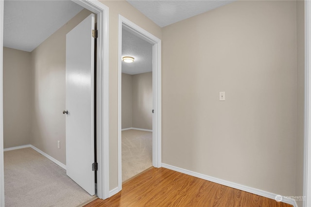 hallway with light hardwood / wood-style flooring and a textured ceiling