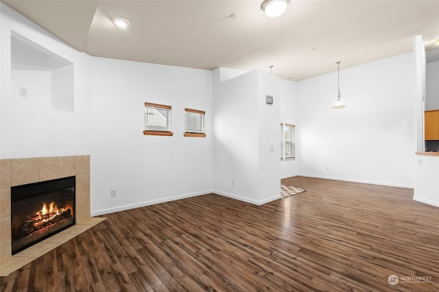 unfurnished living room featuring hardwood / wood-style flooring, vaulted ceiling, and a tile fireplace