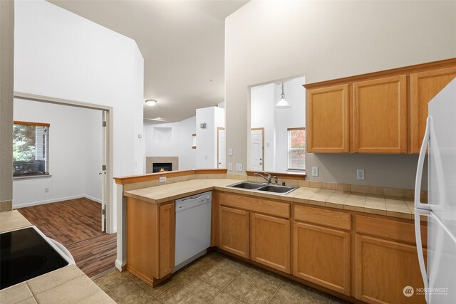 kitchen featuring sink, white appliances, tile countertops, and hanging light fixtures