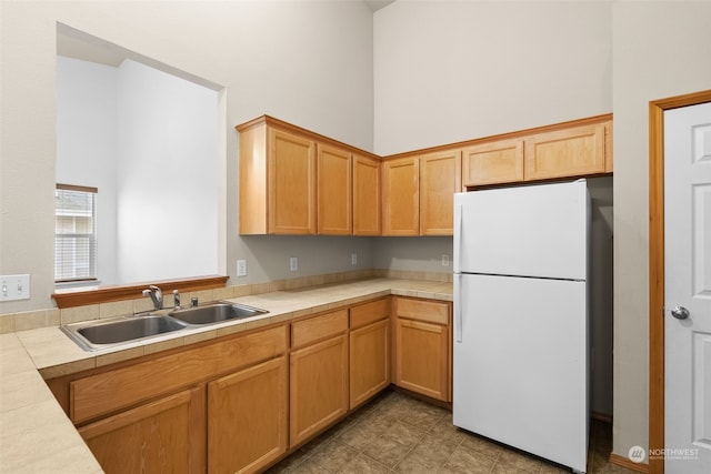 kitchen featuring sink, white fridge, and a high ceiling