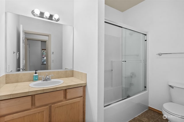 full bathroom with tile patterned flooring, vanity, combined bath / shower with glass door, and toilet