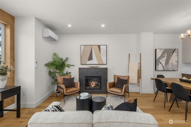 living room with a chandelier, light hardwood / wood-style floors, and a wall unit AC