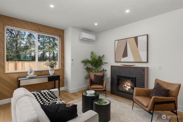 living room with a wall mounted air conditioner, light wood-type flooring, and wood walls