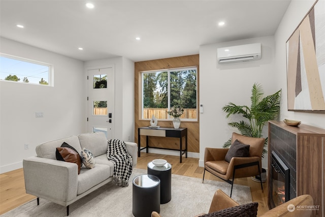 interior space featuring a fireplace, plenty of natural light, a wall mounted AC, and light wood-type flooring