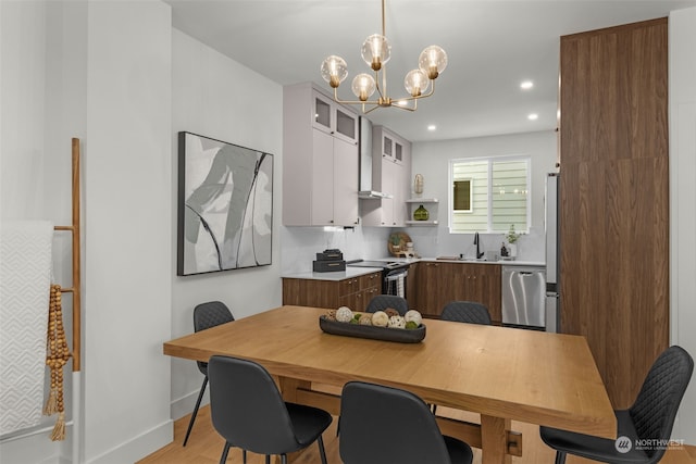 kitchen featuring sink, stainless steel appliances, light hardwood / wood-style floors, white cabinets, and decorative light fixtures