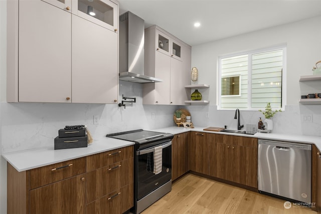 kitchen with wall chimney exhaust hood, white cabinetry, stainless steel appliances, light hardwood / wood-style floors, and backsplash