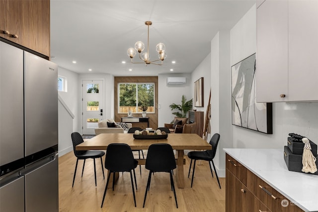 dining space with an inviting chandelier, a wall mounted air conditioner, and light hardwood / wood-style floors