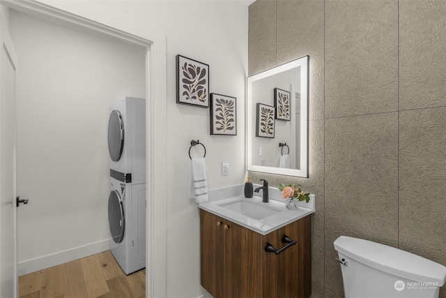 bathroom with vanity, stacked washer / drying machine, wood-type flooring, and toilet