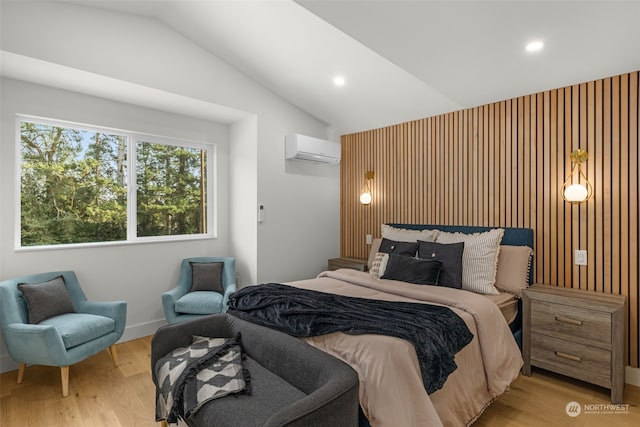 bedroom featuring vaulted ceiling, light hardwood / wood-style floors, and an AC wall unit