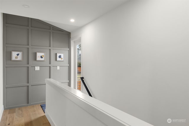 corridor with vaulted ceiling and light wood-type flooring