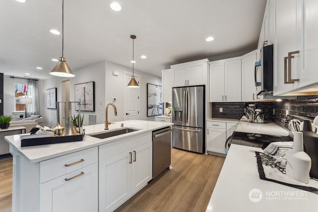 kitchen with hanging light fixtures, stainless steel appliances, and white cabinets